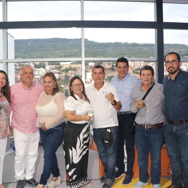 Grupo de personas sonríe y brinda durante la inauguración del Parque Cajasan San Gil, con vista panorámica de la ciudad al fondo
